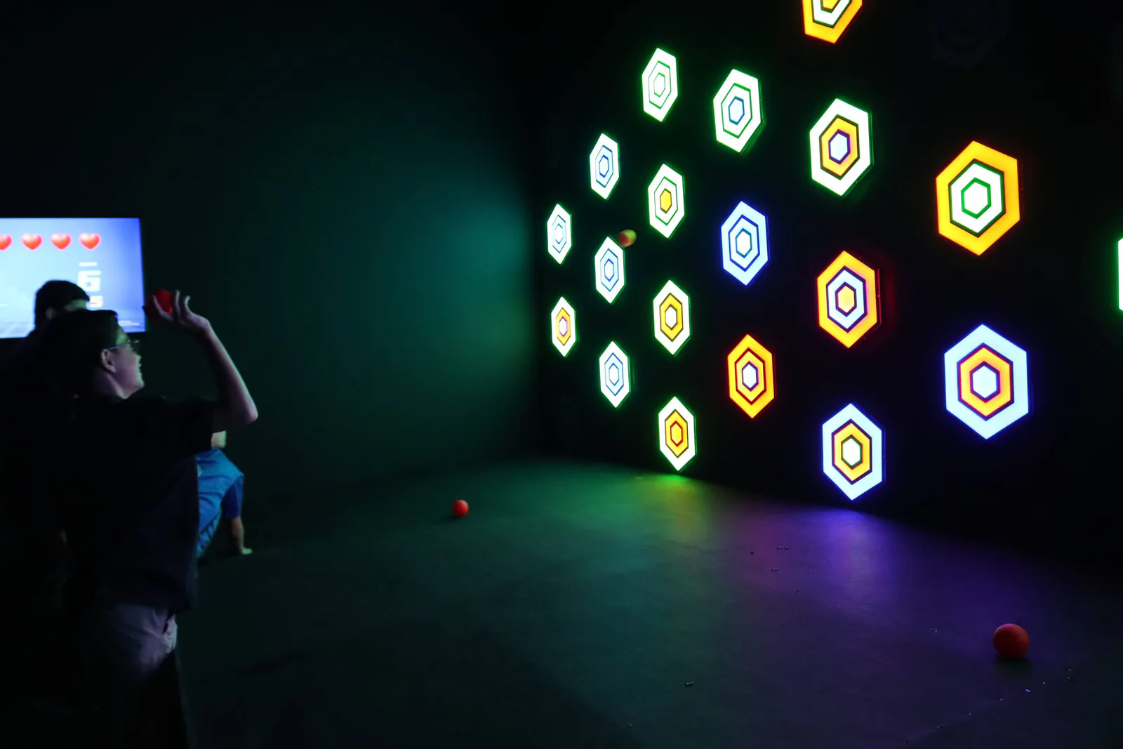 Jugadores frente a la pared de hexágonos iluminados de Centro Mágico