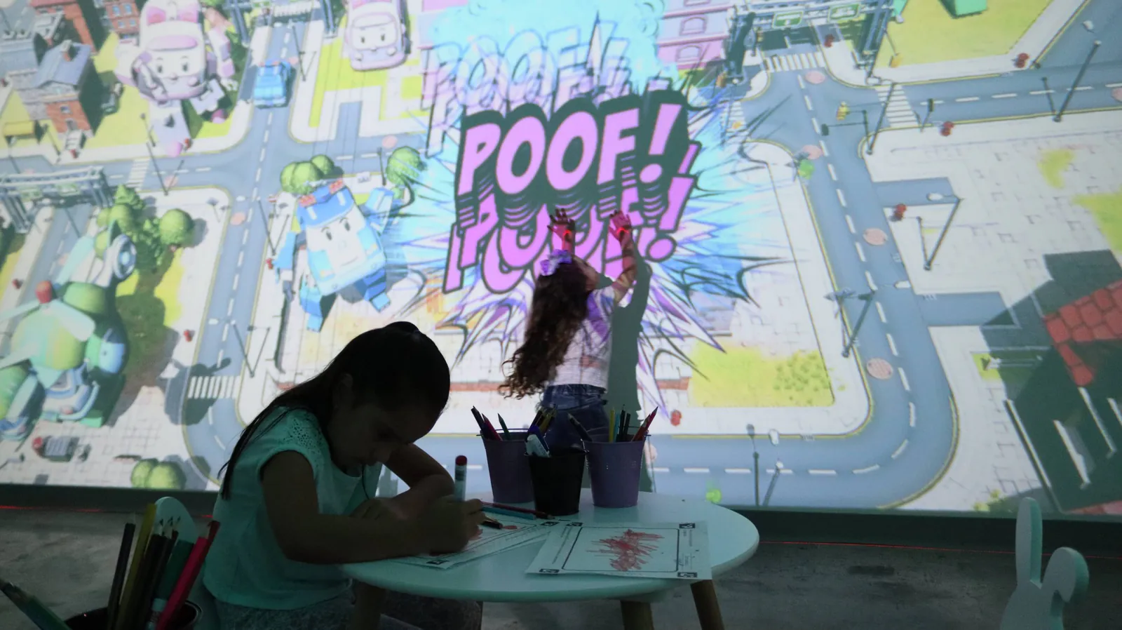 Dos niñas en Mundo Digital: una colorea y la otra toca su dibujo proyectado en la pared